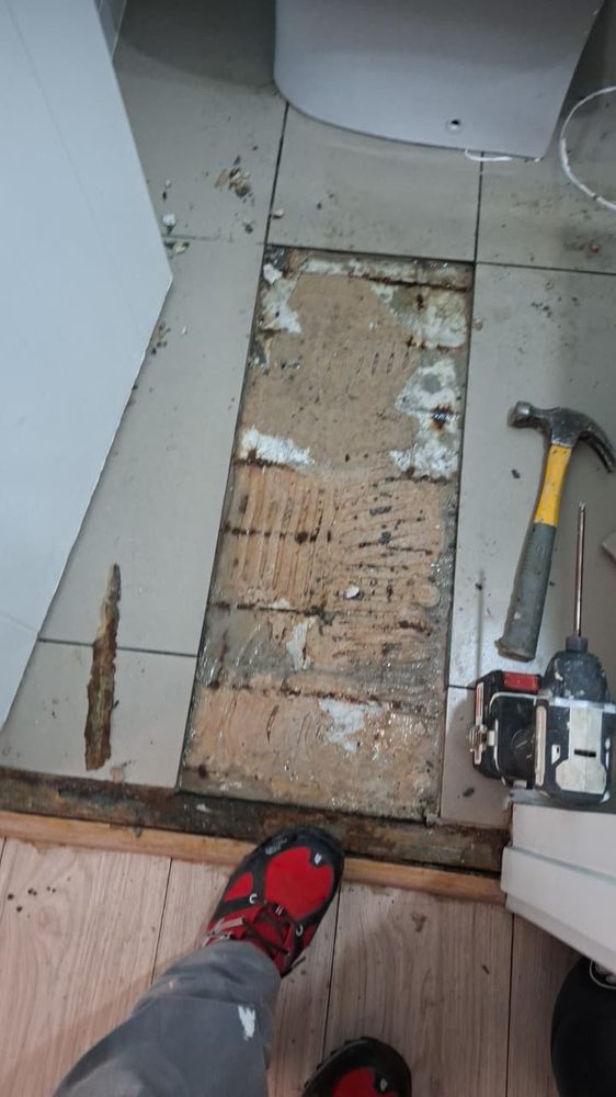 Piso del baño abierto: baldosas retiradas y adhesivo antiguo a la vista